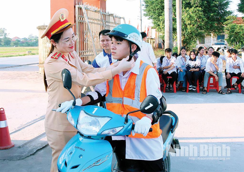 Cán bộ Phòng Cảnh sát giao thông (Công an tỉnh) hướng dẫn học sinh Trường THPT Bắc Lý đội mũ bảo hiểm đúng quy cách.