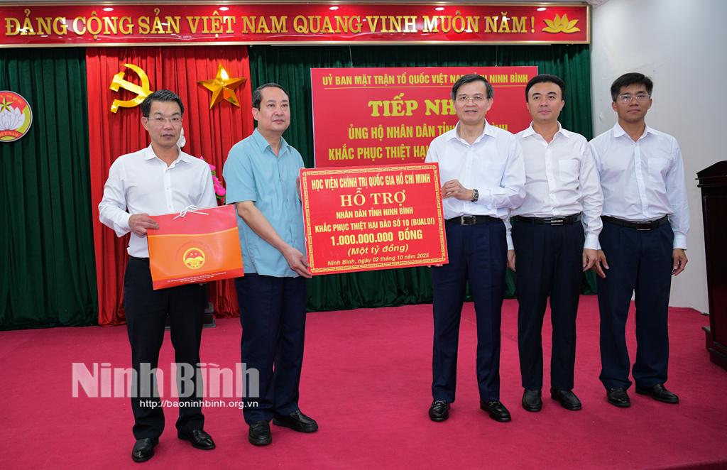 Đồng chí Đoàn Minh Huấn, Ủy viên Trung ương Đảng, Phó Giám đốc Thường trực Học viện Chính trị Quốc gia Hồ Chí Minh trao bảng biểu trưng số tiền hỗ trợ nhân dân tỉnh Ninh Bình khắc phục thiệt hại do cơn bão số 10 gây ra.