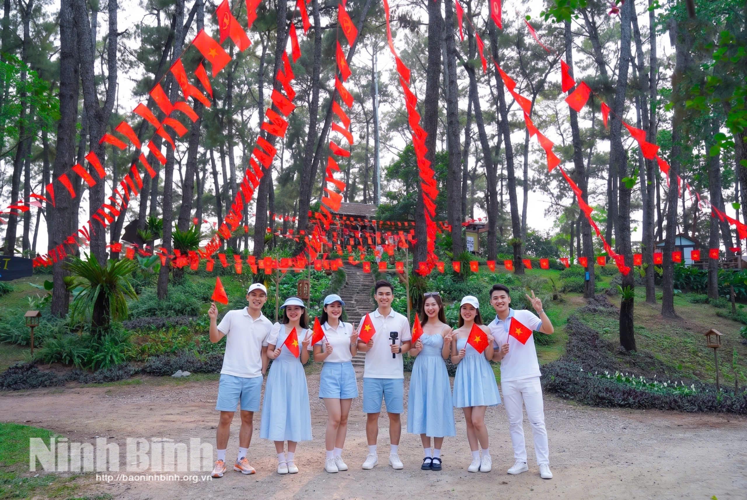 Du khách chụp ảnh với không gian rực rỡ cờ hoa tại Khu du lịch sinh thái Hồ Đồng Chương.