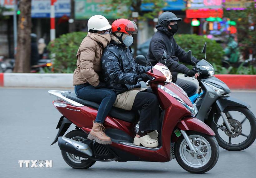 Người dân mặc áo ấm, khẩu trang, khăn quàng cổ, găng tay khi phải di chuyển ngoài trời. (Ảnh: Hoàng Hiếu/TTXVN)