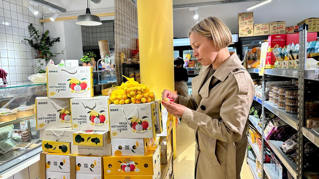 Một khách hàng Pháp đang nếm thử trái vải thiều đầu tiên của mùa vụ 2025 của Việt Nam. Ảnh: TTXVN