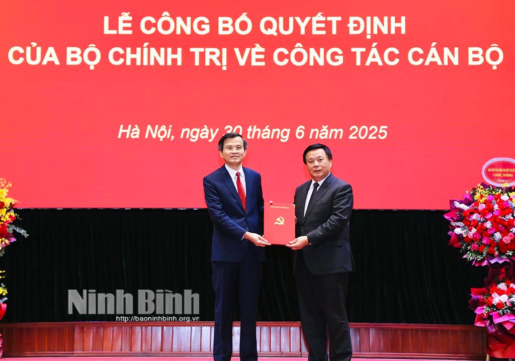 Đồng chí Nguyễn Xuân Thắng, Ủy viên Bộ Chính trị, Giám đốc Học viện Chính trị Quốc gia Hồ Chí Minh, Chủ tịch Hội đồng Lý luận Trung ương trao Quyết định của Bộ Chính trị cho đồng chí Đoàn Minh Huấn.