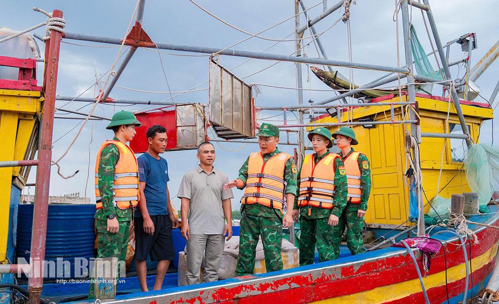 Thiếu tá Dương Ngọc Cương, Trạm trưởng Trạm Biên phòng Cửa Đáy cùng đồng đội hướng dẫn ngư dân các biện pháp neo đậu tàu thuyền an toàn.