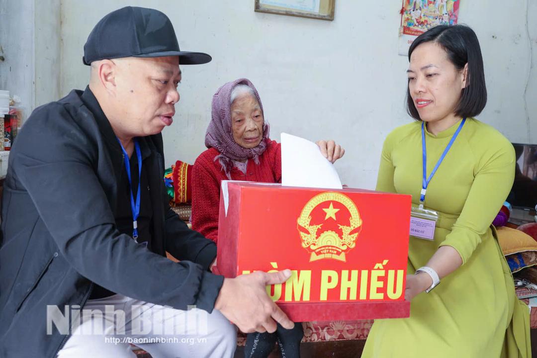 Cán bộ Tổ bầu cử số 42 (tổ dân phố Liễu Văn, phường Nam Định) đưa hòm phiếu phụ đến tận nhà cử tri Trần Thị Gái (97 tuổi) để thực hiện quyền bầu cử. Ảnh: Viết Dư